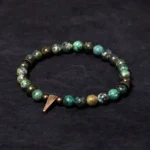 Turquoise copper spike bracelet with vintage antiqued copper charm and natural turquoise beads in overhead flat lay view