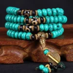 108 bead turquoise dzi Buddhist prayer mala on wooden stand with gold hardware detail