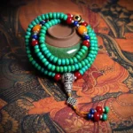 108 Buddhist prayer mala bracelet with turquoise beads and hand-painted dzi bead on ethnic fabric background