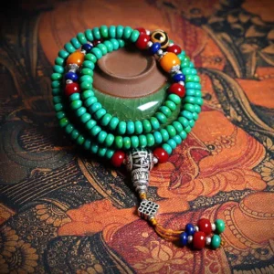 108 Buddhist prayer mala bracelet with turquoise beads and hand-painted dzi bead on ethnic fabric background