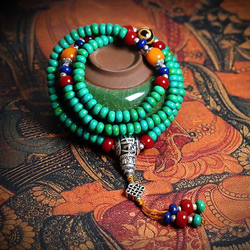 108 Buddhist prayer mala bracelet with turquoise beads and hand-painted dzi bead on ethnic fabric background