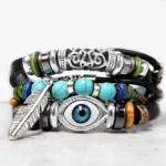 Turquoise Evil Eye Buddhist protection bracelet with silver feather charm, frontal view on gray background