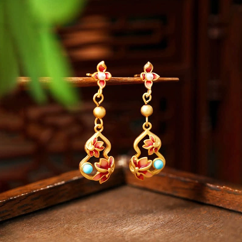 Turquoise cloisonné lotus drop earrings with copper alloy and genuine turquoise accents displayed on wooden tray with green foliage, front hanging view of Buddhist enlightenment earrings