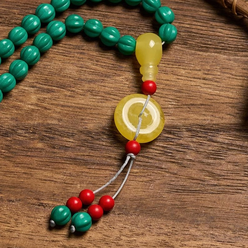 Close-up detail of turquoise mala set showing bead texture, amber pendant and decorative tassel on wooden background