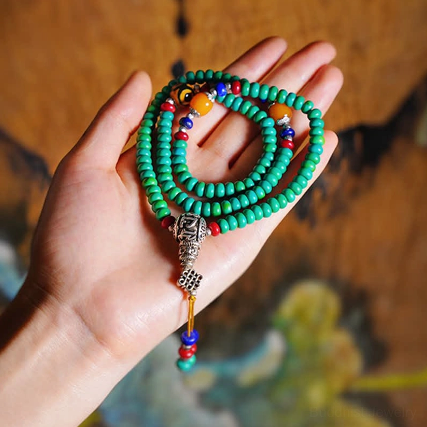 Handheld 108-bead turquoise mala bracelet showing dzi stone and silver tassel details