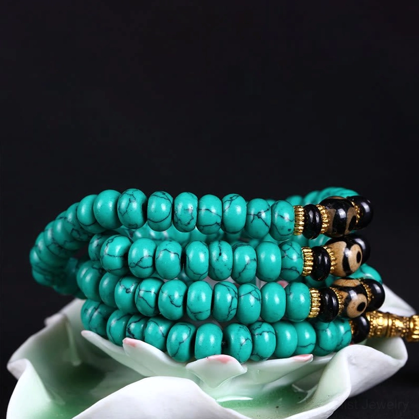 Turquoise bead mala coiled in white lotus holder with black dzi accent beads
