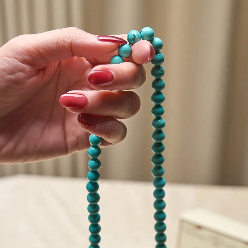 Hand holding turquoise mala beads close-up showing individual gemstone quality and bead segments