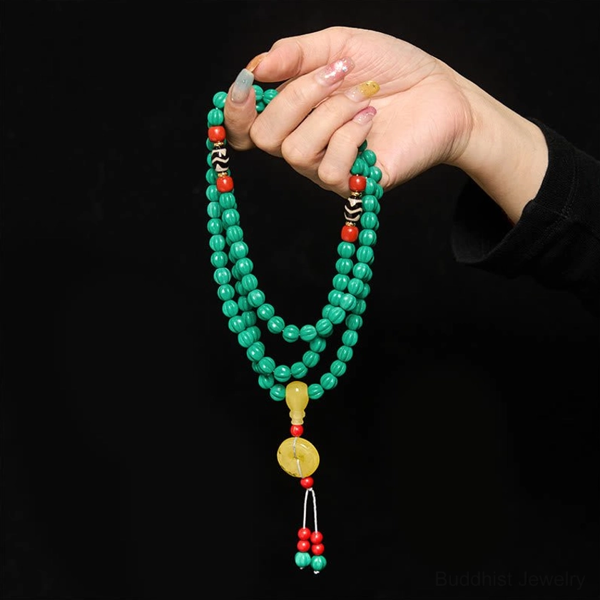 Hand-held turquoise prayer mala close-up showing individual bead quality and dzi bead detail against black background