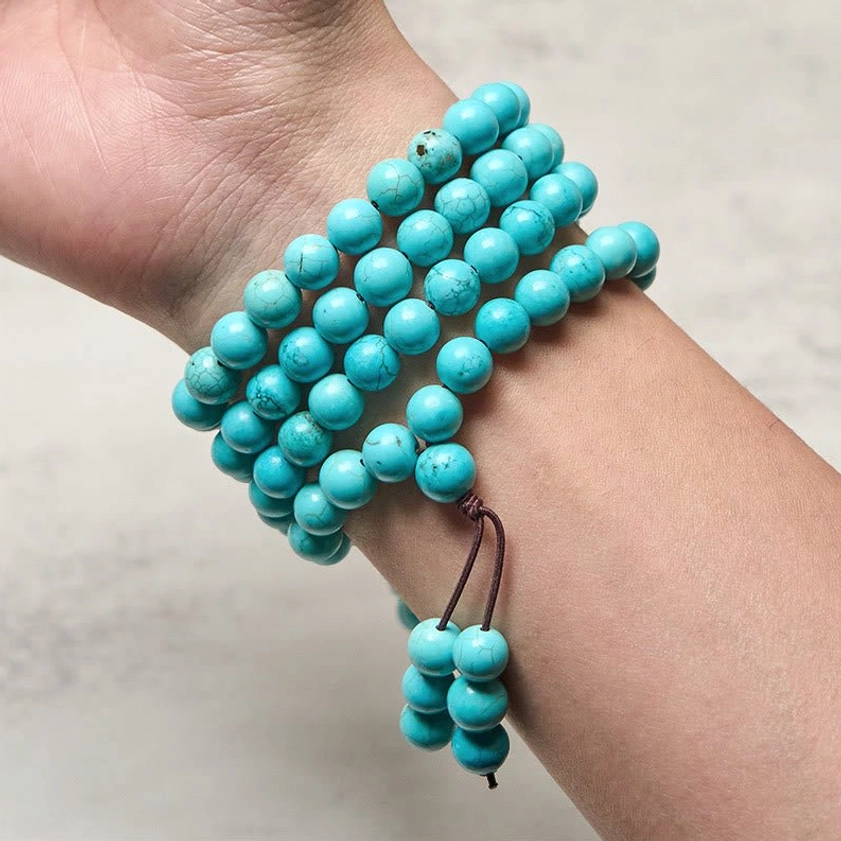 Turquoise mala beads wrapped around wrist showing how to wear as meditation bracelet with hanging tassel
