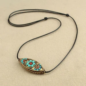 Turquoise marquise Buddhist necklace pendant with red beads on black wax rope, flat lay view on light background