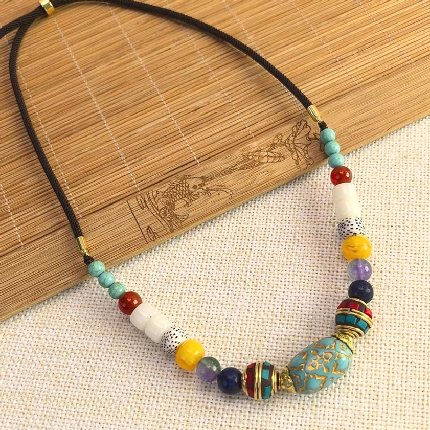 Artisanal turquoise Buddhist necklace on bamboo mat with linen, handcrafted beaded pendant styling
