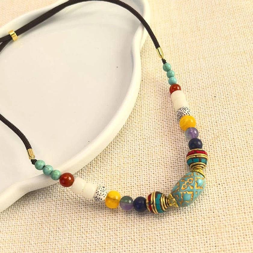 Buddhist turquoise beaded necklace pendant layout on white ceramic tray over linen fabric background