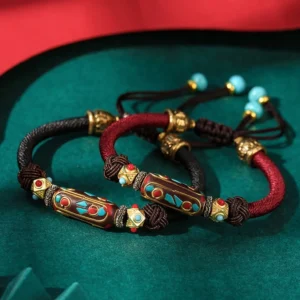 Handmade turquoise Om Mani Padme Hum braided Buddhist bracelet with enamel charm in burgundy red and brown woven cords, displayed flat lay on dark green velvet background