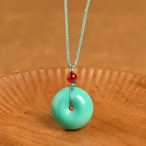 Turquoise peace buckle Buddhist necklace pendant - front flat lay view on wooden tray