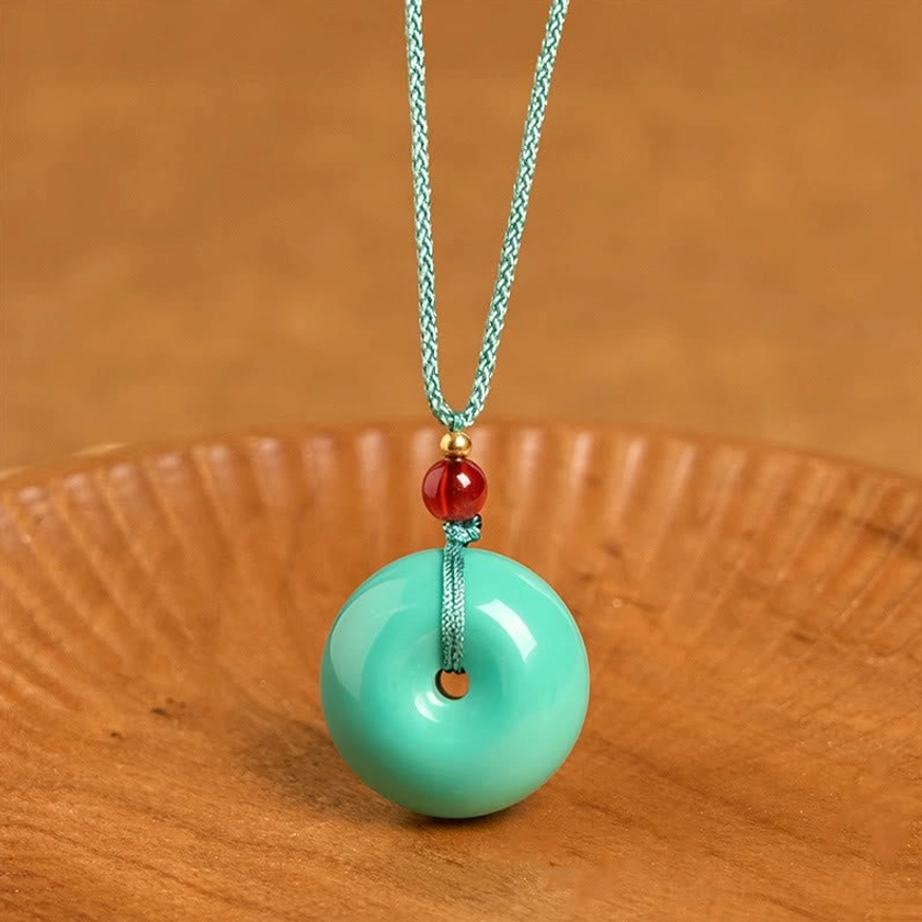 Turquoise peace buckle Buddhist necklace pendant - front flat lay view on wooden tray