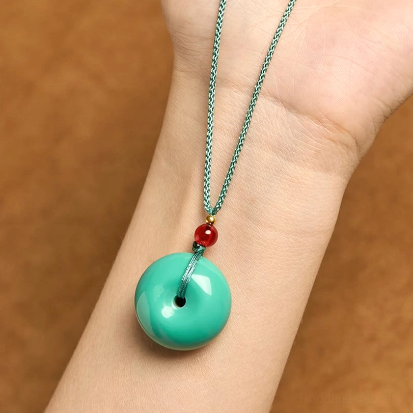 Turquoise peace buckle necklace worn on wrist - Buddhist pendant in-use lifestyle shot