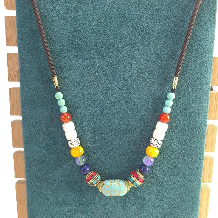 Natural turquoise beaded Buddhist necklace with brown wax cord on velvet fabric with wooden blocks