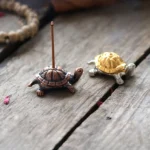 Handcrafted bronze turtle Buddhist incense holder on rustic wooden desk with copper base and decorative accent