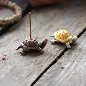 Handcrafted bronze turtle Buddhist incense holder on rustic wooden desk with copper base and decorative accent