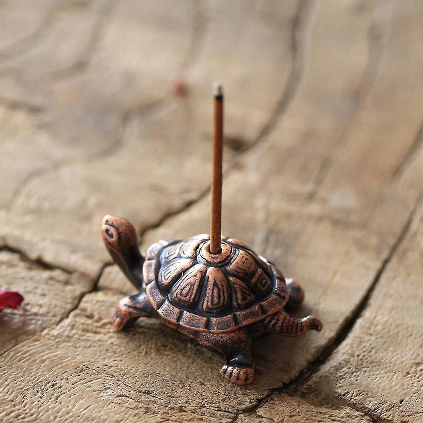 Vintage copper turtle incense holder front view with carved shell patterns and inserted incense stick on wooden surface
