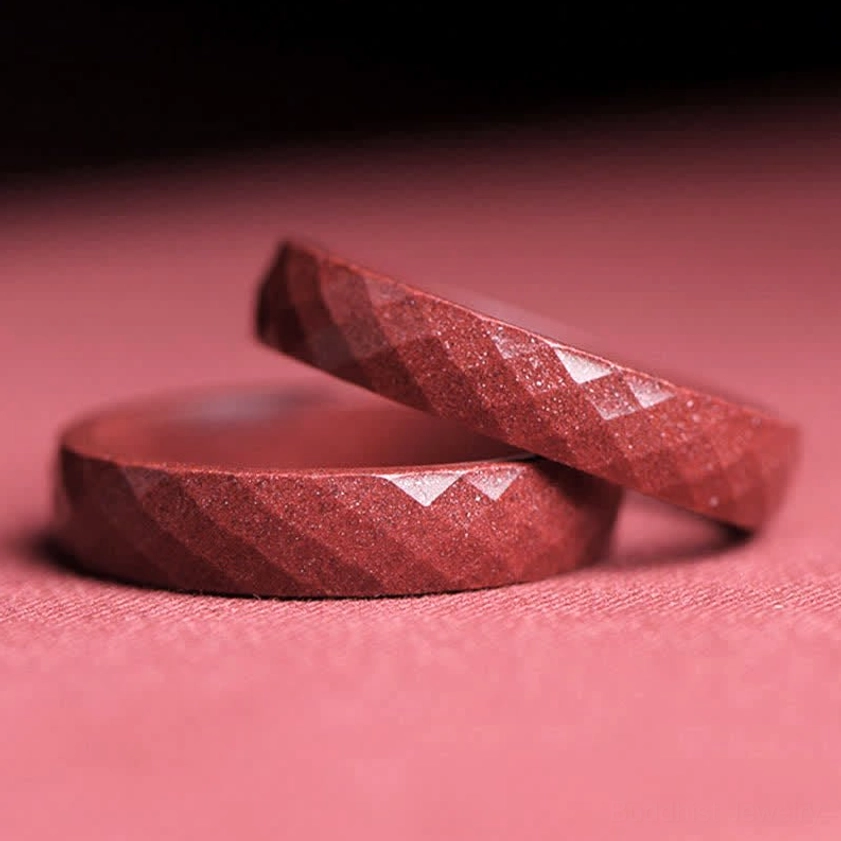 Two stacked faceted cinnabar blessing rings showing matching diamond-cut designs and rich reddish-brown color