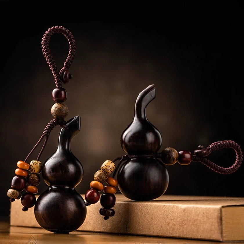 Two handmade Buddhist gourd keychains with different braided rope styles, front view on kraft book background for meditation and protection