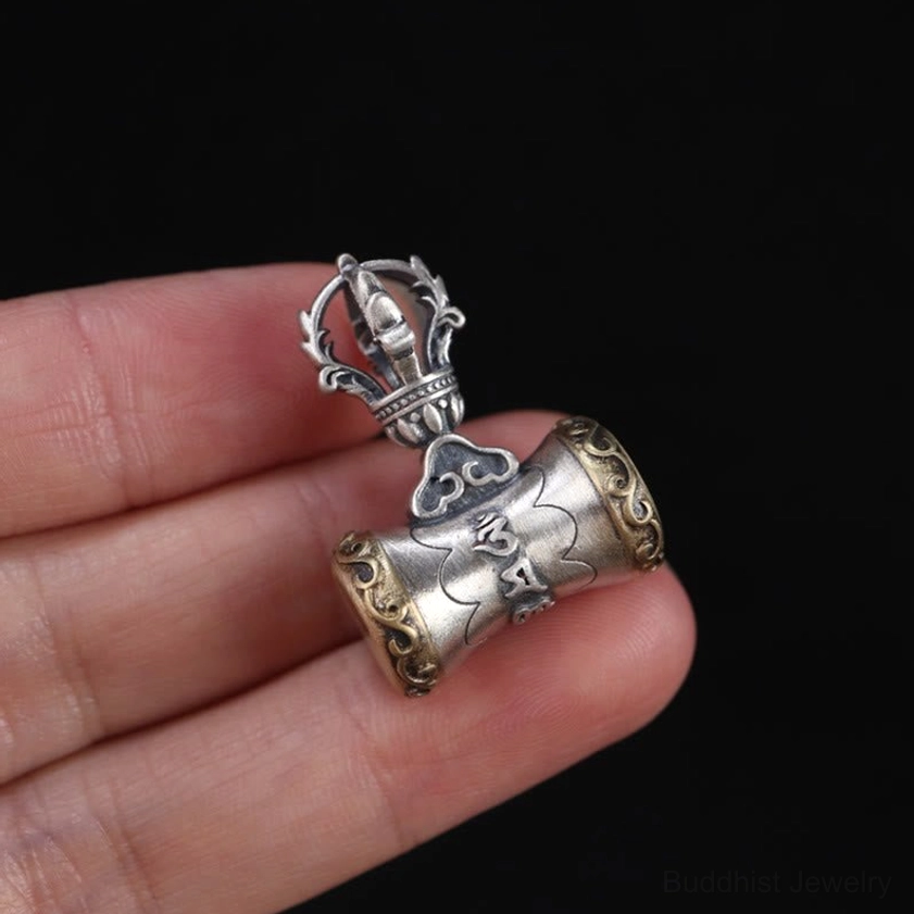 Sterling silver vajra bell pendant with Om Mani Padme Hum mantra worn on traditional cord for spiritual practice
