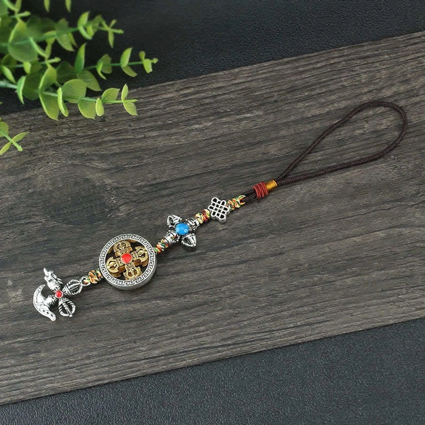 Compact vajra car hanging decoration with blue faux gemstone and metal chain against dark wooden background