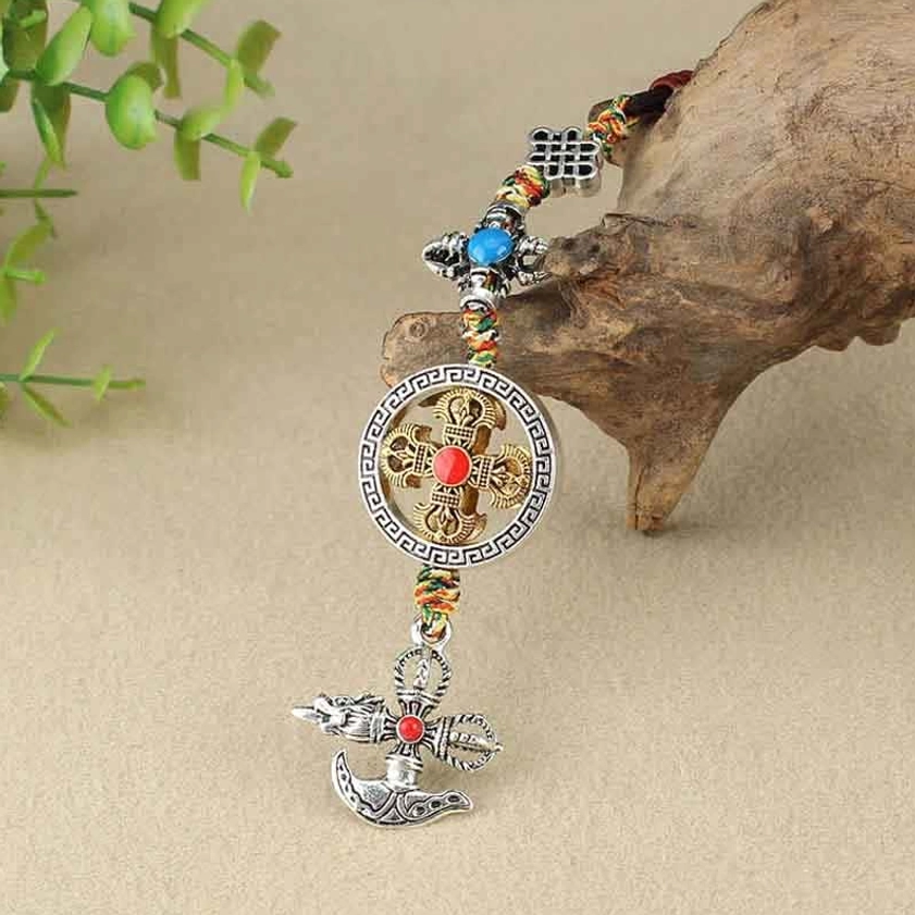 Vajra spiritual power ornament showing hollowed cross pendant with knot charm detail against wooden background
