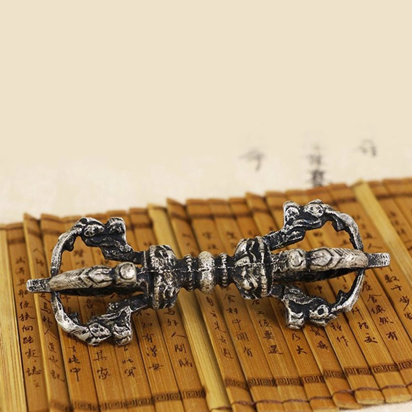 Close-up of individual vajra dorje showing intricate religious carvings and dark silver copper tone