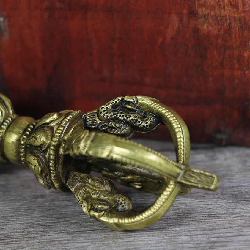 Extreme close-up of copper vajra dorje showing relief dragon motifs and five-pronged ring ends in detail