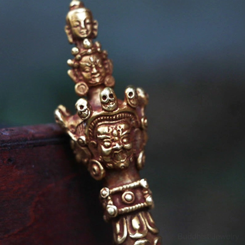 Close-up detailed view of Vajra Dorje handle showing wrathful deity faces, skull ornaments, and multi-layered carved bands