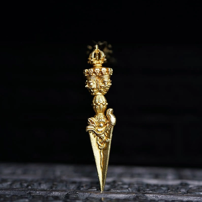 Brass vajra dorje spiritual pendant with religious engravings displayed on dark base front view