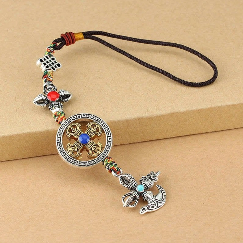 Five-pronged vajra spiritual ornament with brown lanyard, blue gemstone on cross, and hollowed round pendant