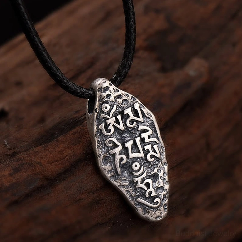 Vajra Om Mani Padme Hum silver pendant top front view, engraved Vajra symbol with S925 sterling mark, irregular artisanal shape on wooden background