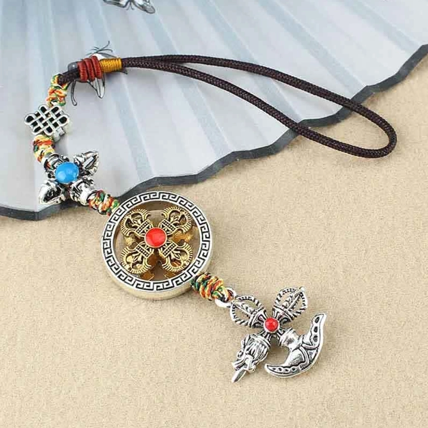 Buddhist vajra hanging ornament with brown rope and Chinese knot accessory, dual-tone metal finish flat lay