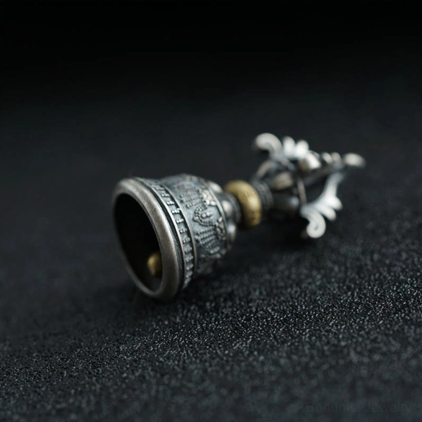 Rear side view of Buddhist vajra bell pendant showcasing embossed patterns and brass accent ring in sterling silver