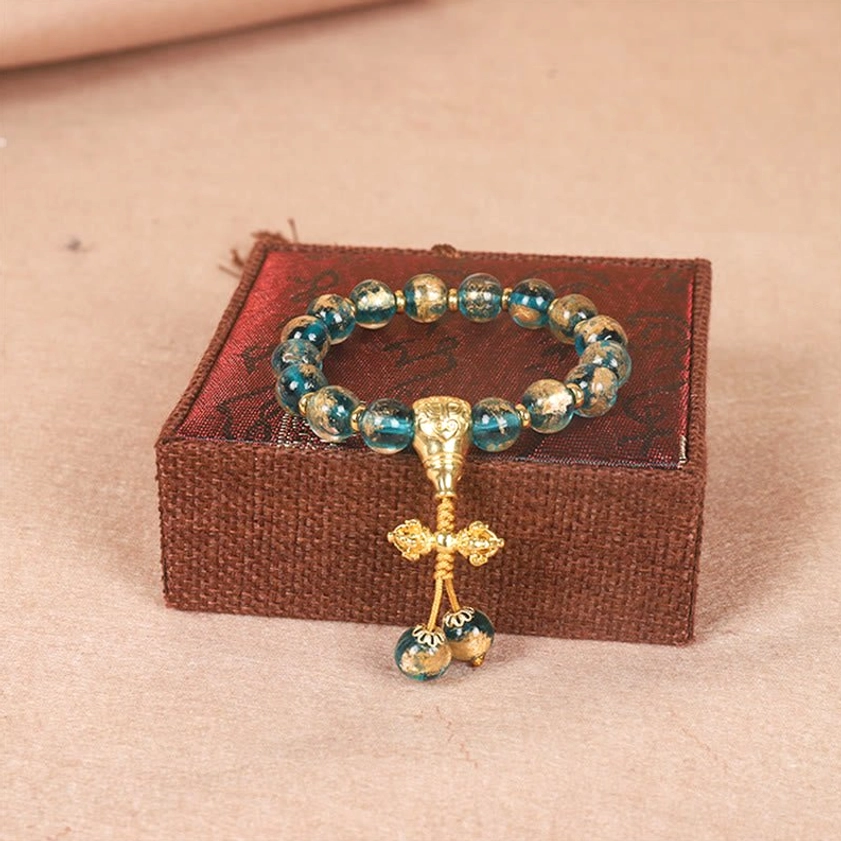 Vajra Buddhist bracelet with teal beads and ornate gold ritual pendant symbolizing spiritual power and enlightenment