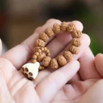 Vajra seed and lotus pod meditation palm stone held in hands showing smooth polished texture and carved lotus pendant detail