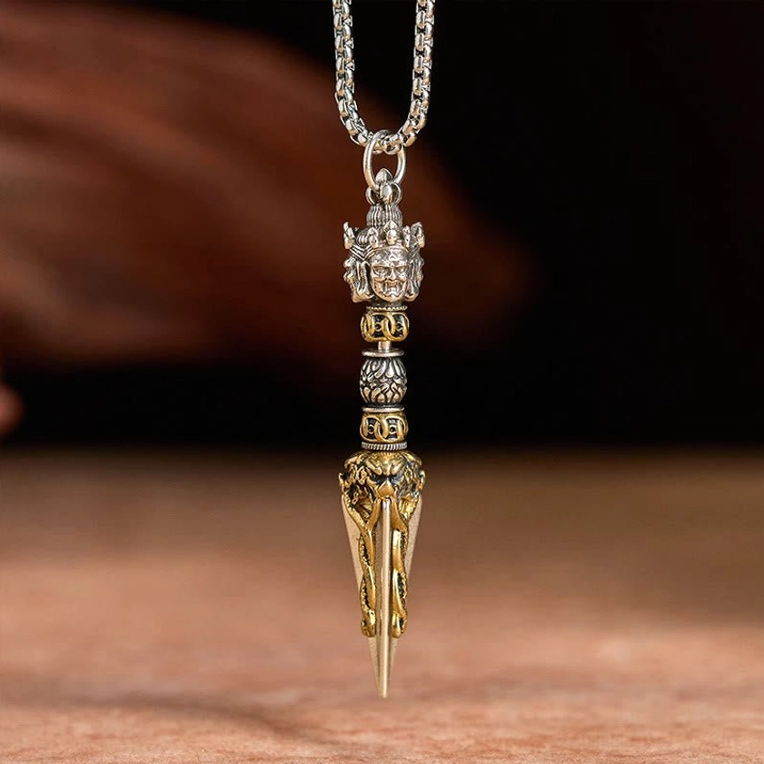 Vajrakila copper Buddhist necklace pendant hanging on silver chain, overhead flat lay view