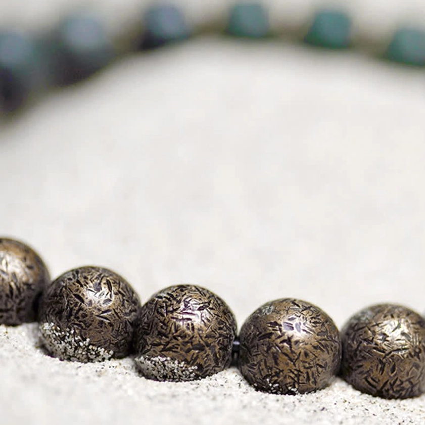 Vintage bronze metal spacer beads macro photography showing textured round brown beads on sand
