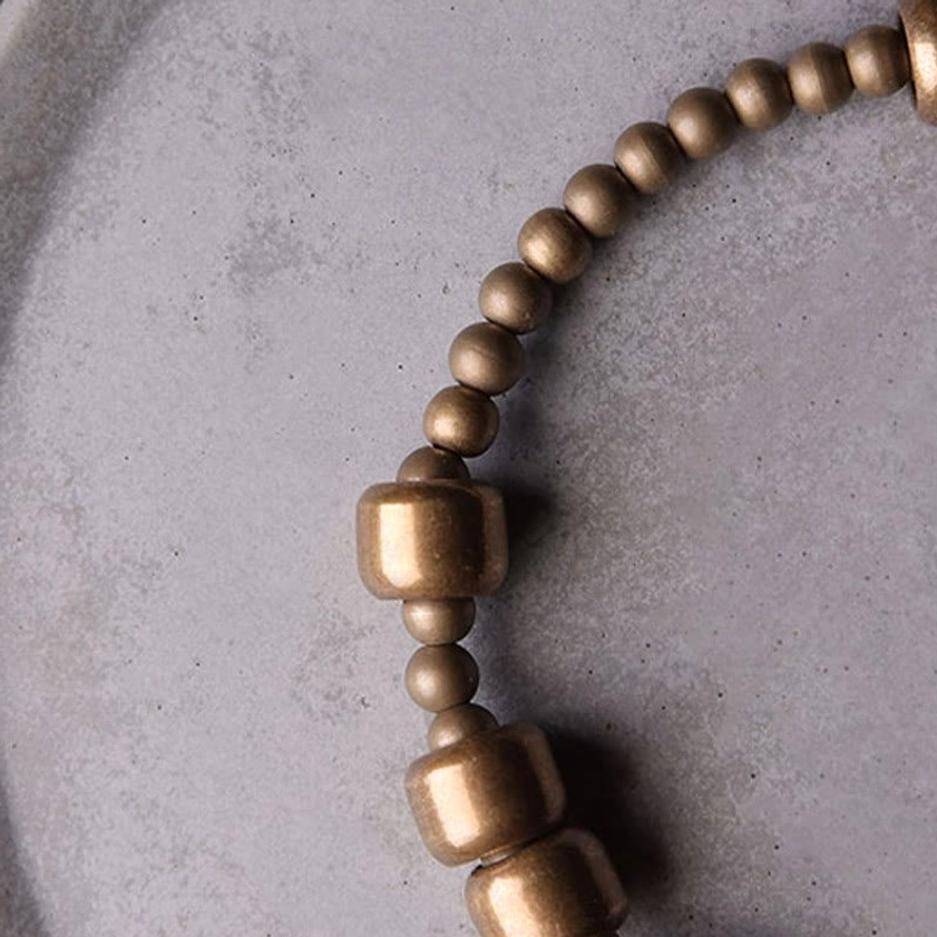 Copper beaded bracelet angled side view showing polished metal alternating barrel and round bead pattern