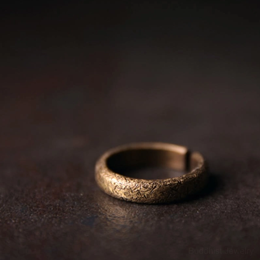 Single vintage copper Buddhist ring with classic bronze tone and rough etched texture, angled side view