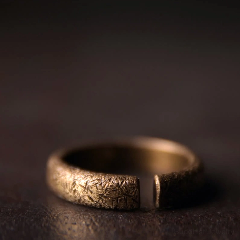 Single vintage copper Buddhist ring with visible open adjustable gap and coarse engraved surface texture