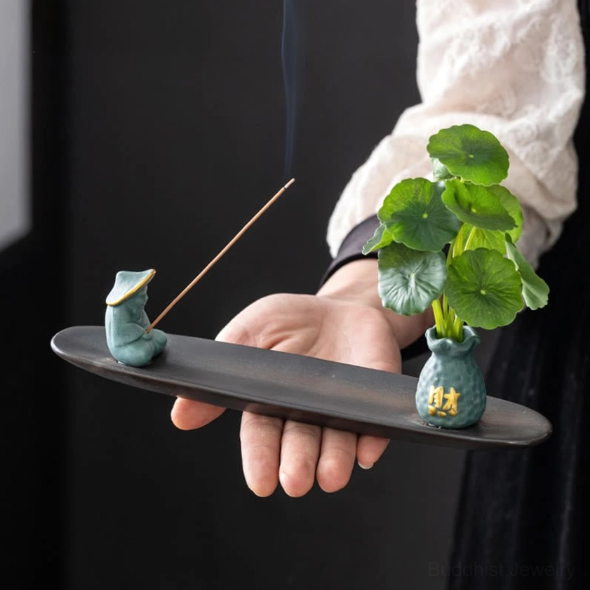 Buddhist incense burner with figurine vase in warm natural tone on wooden surface