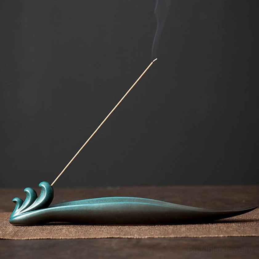 Waves ceramic incense holder with lit incense stick on dark wooden table dark teal matte glaze