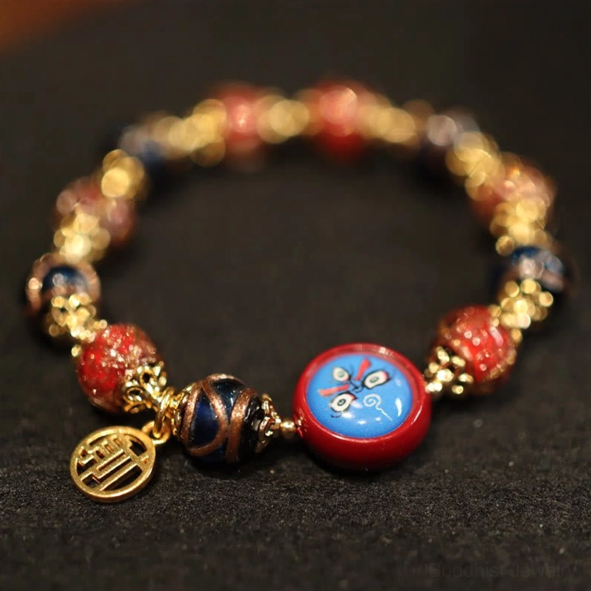 Buddhist wealth bracelet with blue enamel round bead, red accent beads and gold fortune pendant detail shot