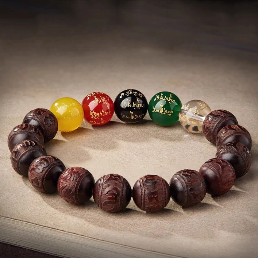 Handcrafted Buddhist wealth bracelet with carved wooden beads and engraved agate accents on brown fabric