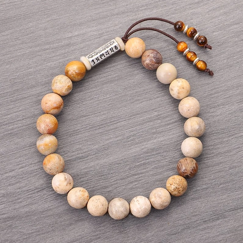 Full view of weathered stone bracelet on grey background displaying complete mantra charm and beaded design