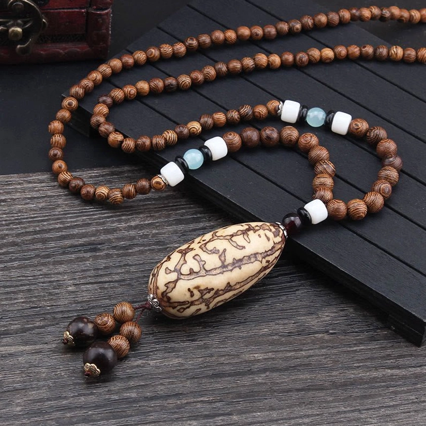 Single Wenge wood Buddhist necklace with patterned Bodhi seed pendant and earthy brown wooden beads on slatted surface